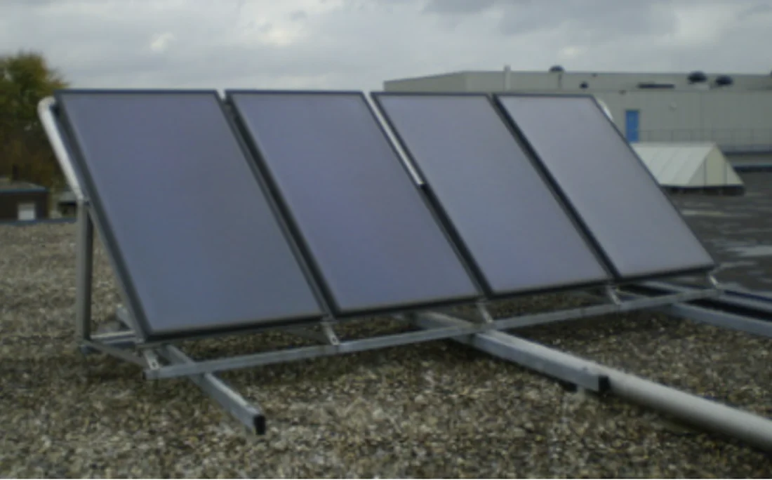 Vier vlakke zonnecollectoren op een plat bedrijfsdak